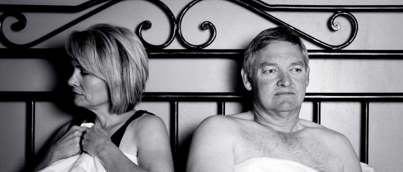 Unglückliches Paar mittleren Alters im Schlafzimmer. Schwarz und weiß.