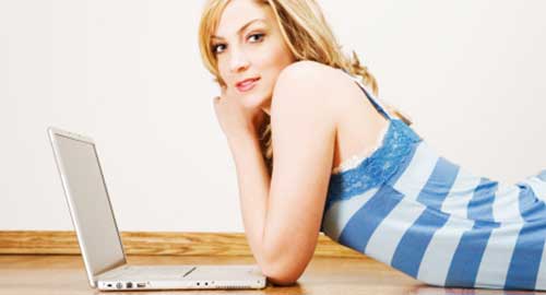 sinnliche blonde Frau vor einem Laptop liegend