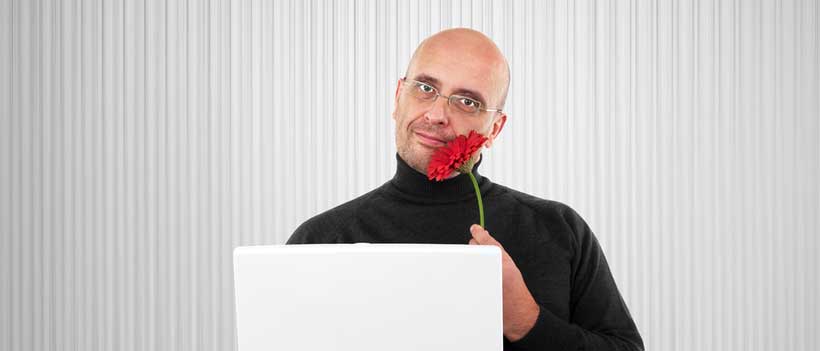 Glatzköpfiger Mann mit einer Blume an der Nase 