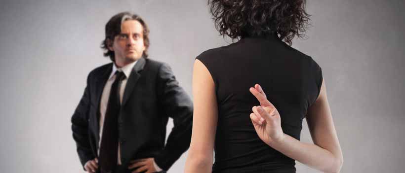 Untreue Frau kreuzt Ihre Finger hinter ihrem Rücken während Sie mit Ihrem Mann spricht