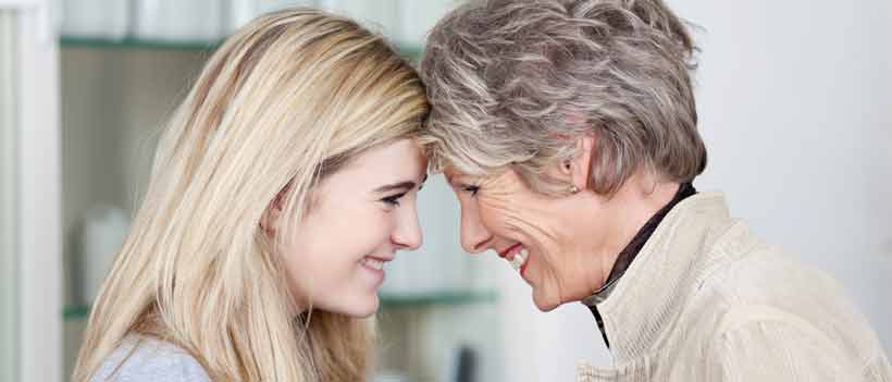 Erwachsene Enkelin und Oma schauen sich tief in die Augen 