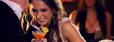 Flirtendes Pärchen mit einem Cocktail auf einer Feier