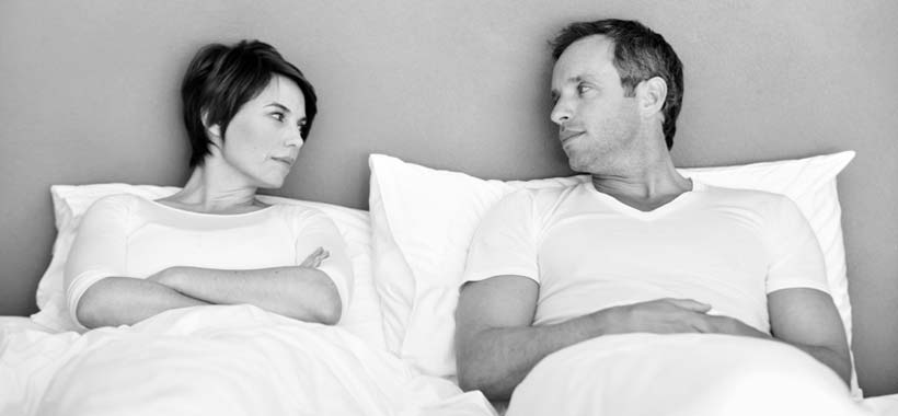 Ein älteres Paar leigt im Bett und hat Meinungsverschiedenheiten